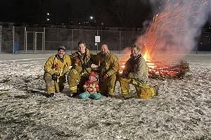 Firefighters pose in front of the Christmas tree bonfire 2025